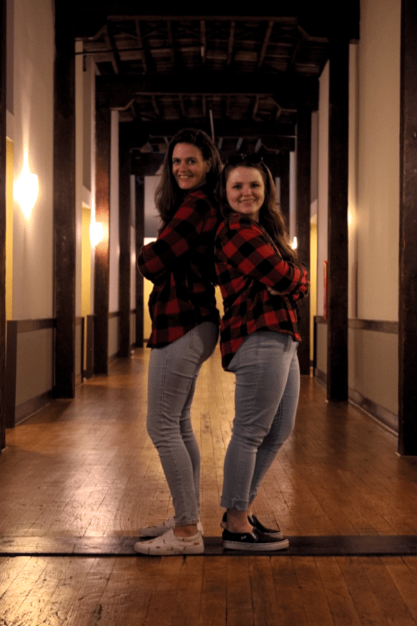 Two Friends Standing Back-To-Back And Smiling